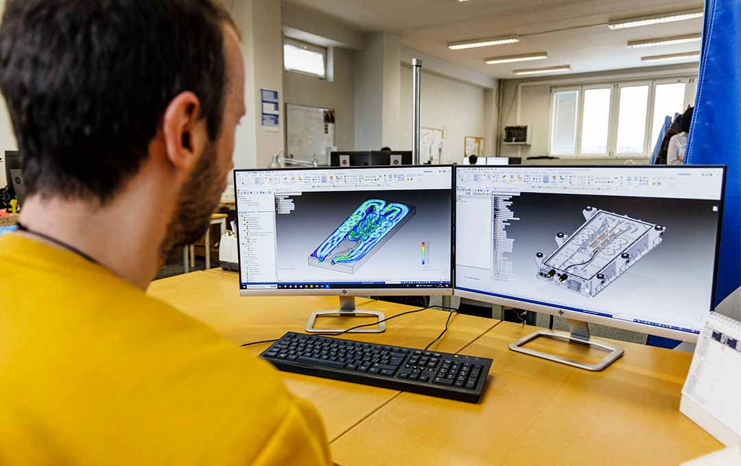 Image of a person looking at 3D model renderings on a computer.