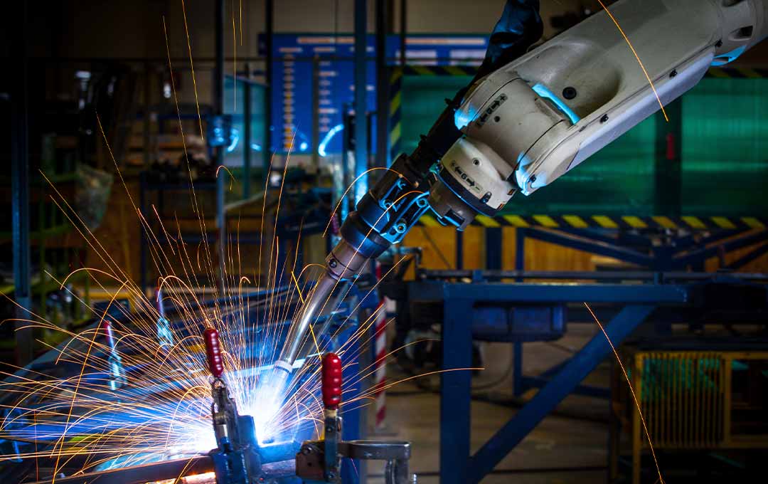 Image of a robotic arm welding an object with sparks flying.
