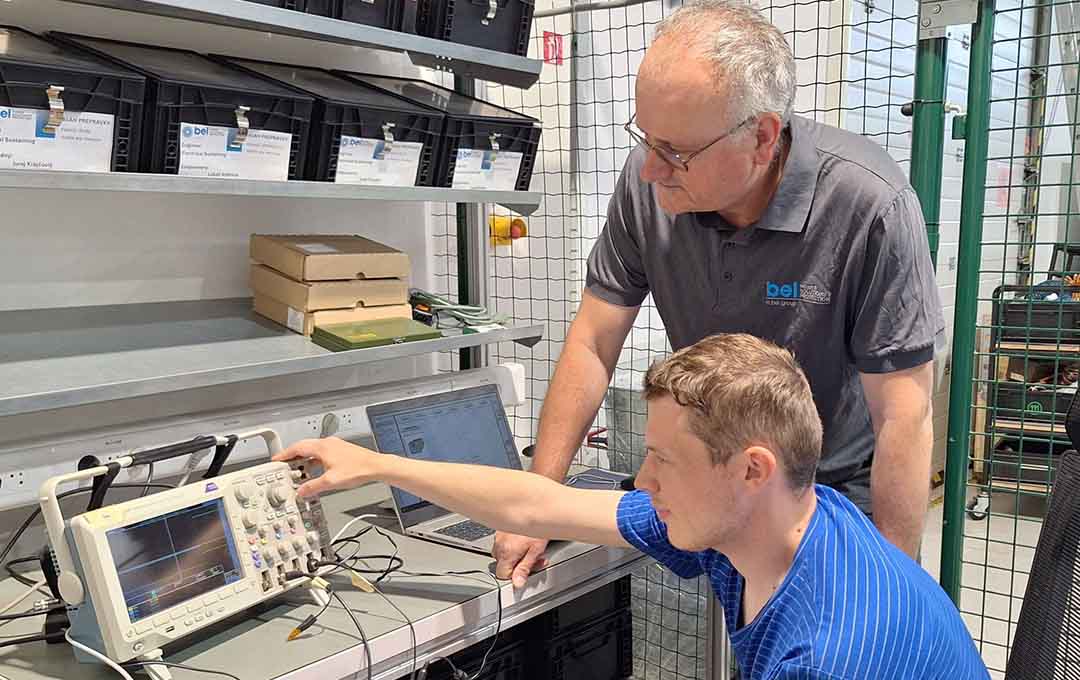 Two Bel employees at a desk using a piece of equipment.